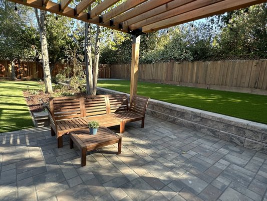 Paver patio with Toja Grid pergola, retaining wall and turf