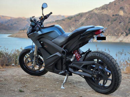 Electric motorcycle parked with reservoir in background