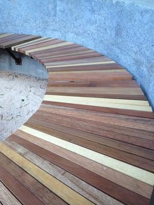 Custom made curved bench, made from reclaimed Japanese railroad ties, set into a cast concrete wall...