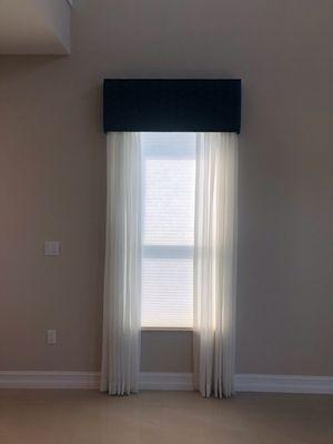 Light filtering cellular shade with decorative, sheer drapery side panels, and a fabric-wrapped cornice.