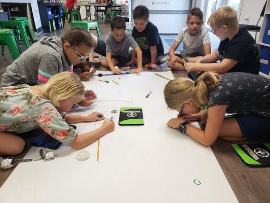 Students build a robotic racecourse using color codes to program their Ozobots.