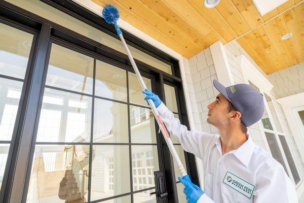 Green Pest Management technician de-webbing a home.