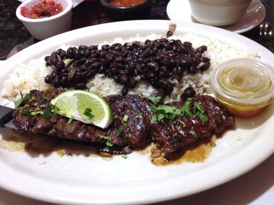 Grilled skirt steak and onions served with a side of white rice and black beans