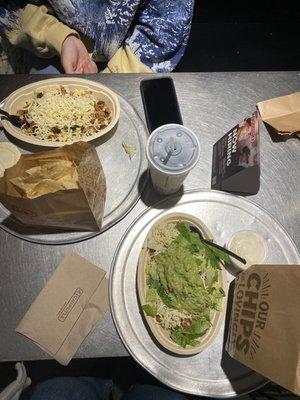 Two steak bowls (one with guacamole) and two servings of chips and queso.