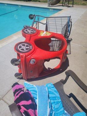 Grocery cart left in pool are by kids after playing on it around and in pool