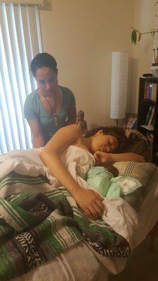 New mama enjoying a postpartum healing massage while nursing her baby girl.