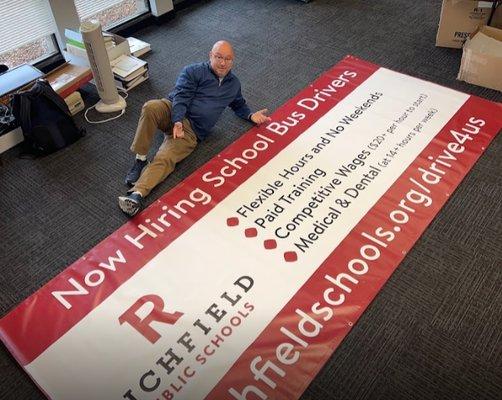 Owner with a large banner completed for Richfield Public Schools