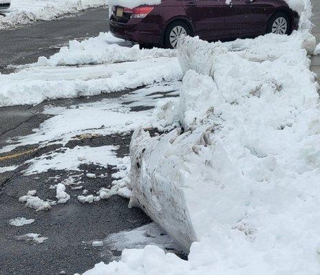 Cmark freshly plowed parking spaces with snow piled in front of parking spaces to impede access to units snd sidewalk.