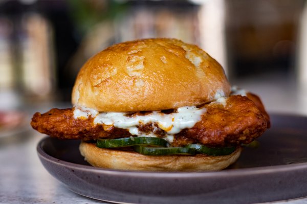 Buffalo Chicken Sandwich | breaded chicken tenders tossed in buffalo sauce, housemade pickles, grilled bun, bleu cheese aioli (GF available)