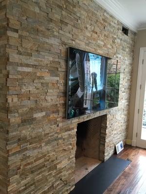 Samsung 75" 4K Ultra HDTV mounted on a Stone fireplace with an articulating arm.