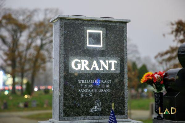 Grant's grey cemetery headstone illuminating at night.