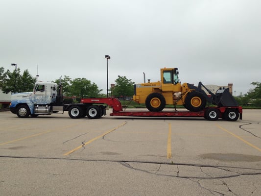 Our Freightliner with a lowboy trailer hauling one of our front-end wheel loaders.