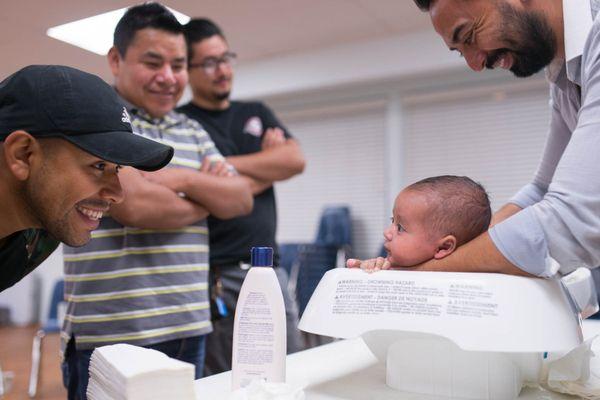 In our Workshop for New Fathers, veteran dads and their new infants mentor fathers-to-be in diapering, feeding, swaddling, bathing, etc.