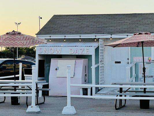 Snow cone stand and picnic tables with umbrellas to hang out. Patio lights and neon Open sign.