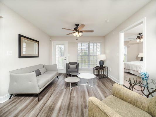 Living room area with ceiling fan and wood like floors