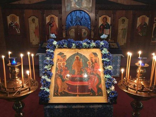 An icon of the Dormition of the Theotokos decorated with flowers for the feast.