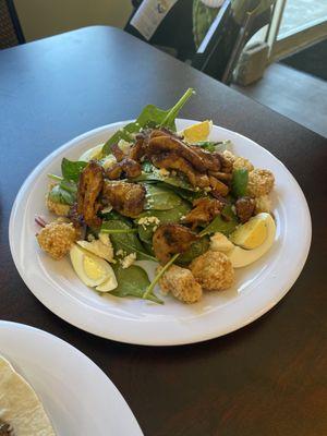 Spinach salad with eggplant croutons, topped with chicken shawarma .