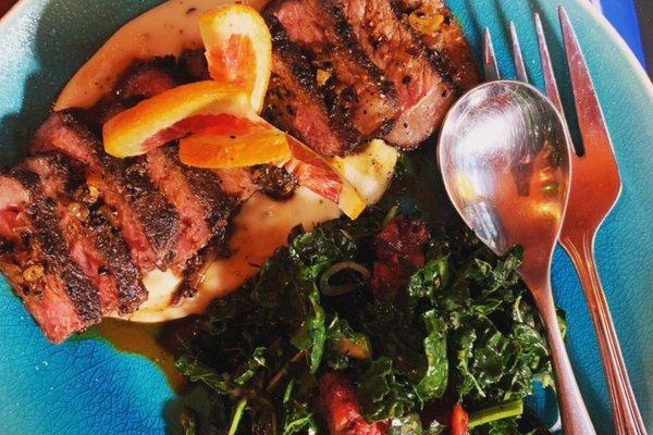 Bison steak on top of a creamy potato puree with a fresh kale and blood orange salad