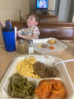 Hamburger steak, yams, Mac n cheese, green beans, cute kid and cornbread.