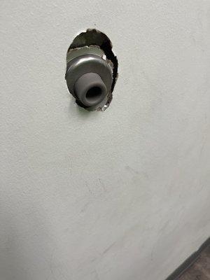 Broken door stopper in the examination room on the dirty wall.