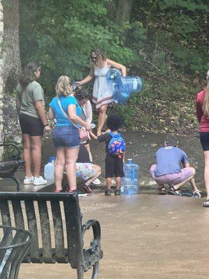 People waiting with 5 gallon bottles to fill with cave springs water