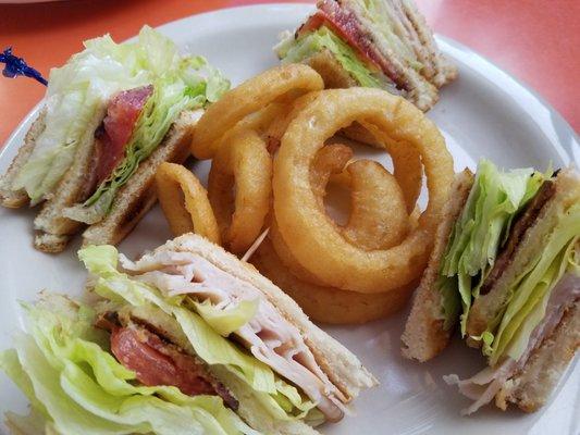 Turkey club on white with perfectly cooked bacon and nice onion rings.