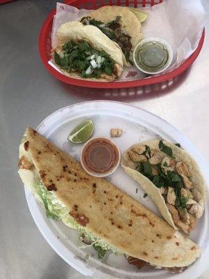 On the red tray: one carnitas taco and one pollo taco. On the white plate: one quesadilla and one pollo taco