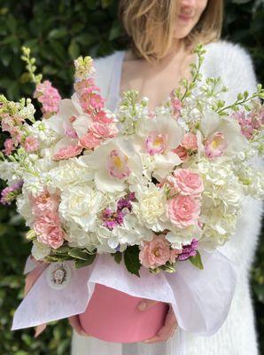 Flower arrangement in a box with roses, hydrangeas and orchid. Soft white and pink colors