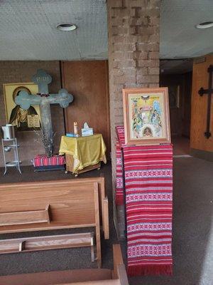 Narthex of church.  Entrance area where candles may be lit before entering church.  Colorful Romanian embroidery other icon stand.