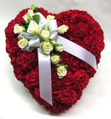 A lush sympathy piece, a red carnation heart with white rose accents