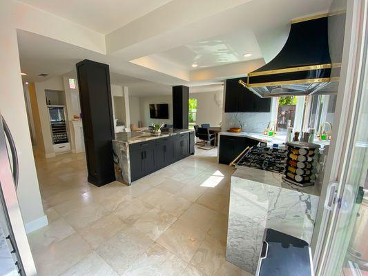 Satin black kitchen cabinets with matching columns. Marble waterfall countertop with a contrasting island marble waterfall countertop.