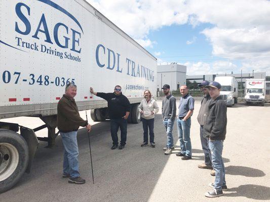 Sage faculty training students outside on the driving range.