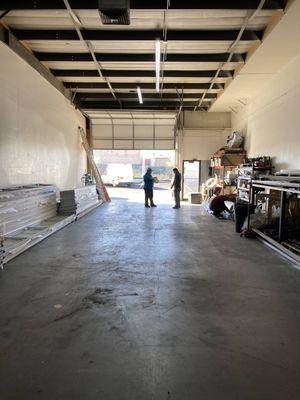 A picture of Unlimited Garage Door Services space looking from inside the building to the outside with the garage door open a...