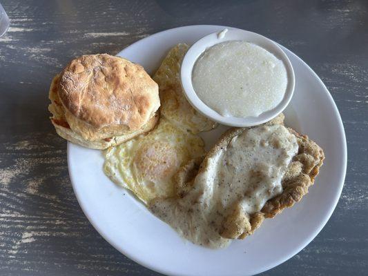 Chicken fried steak, eggs, grits and biscuit.