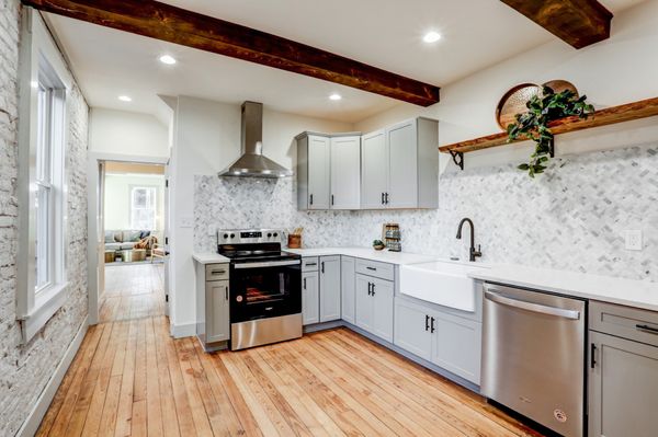 Mosaic tile backsplash, wooden beams added to ceiling, open shelving, gray cabinet kitchen design.