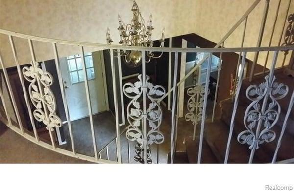 Elegant entry way with winding staircase and hanging chandelier .