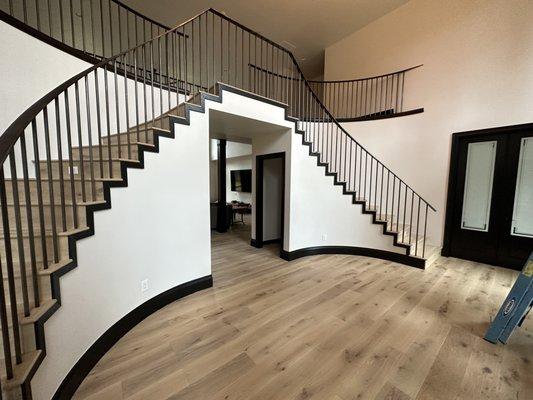 Just completed....Show stopping stair case with wrapped black casing over wide board engineered hardwood.