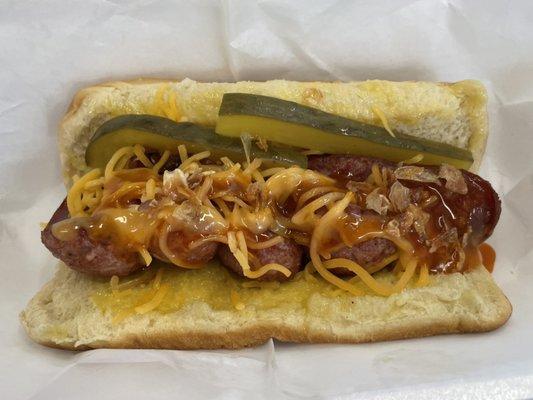 Cajun Dog - fried conecuh sausage in a hot dog bun, topped with cheese, pickles, fried onions, and Bun sauce.