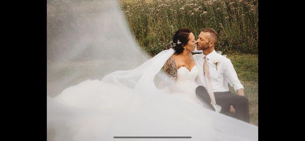 Bride and groom in field being photographed through the veil by cleveland photographer.