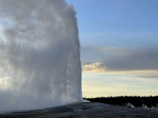 Old faithful erupting at sunset