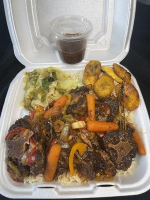 Fall off the bone tender oxtail, with a side of fried plantain, cabbage over rice and peas.