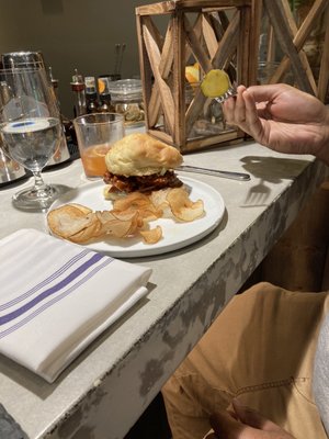 Chipotle fried chicken sandwich with homemade chips, little fatty bourbon cocktail in the back