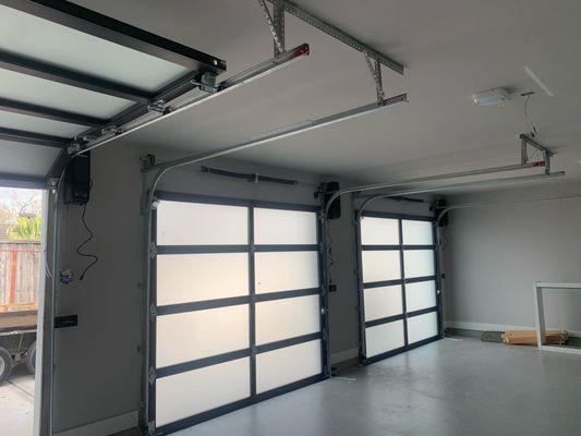 INSIDE GARAGE, FULL VIEW DOORS INSTALLED ALONG WITH LIFTMASTER JACK SHAFT OPERATORS