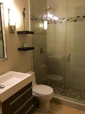 Frame-less glass shower with gorgeous designer tile and new vanity with custom floating shelves. Stainless sconces and new lighting.