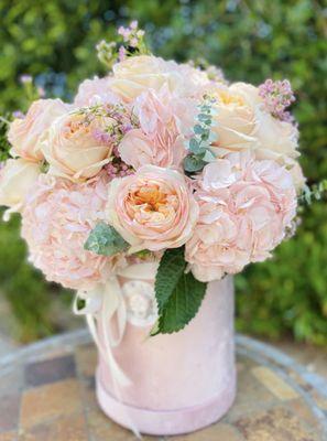 Flower arrangememt in a box in soft pink and peach colors. Garden roses and hydrangeas