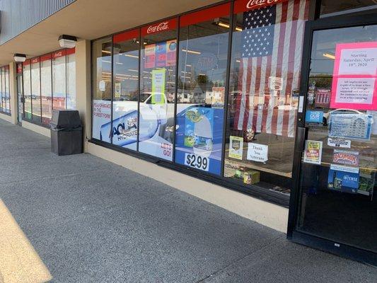 Close up of the store front. Hours of operation, lottery advertisements, etc.