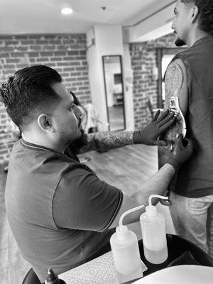 Tattoo Artist Adrian pasting a stencil on a client.