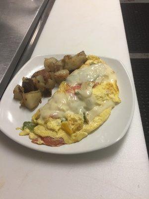 Veggie omelet covered with melted american cheese with a side of home fries