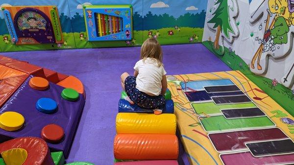 Toddler Play and Roll area, with floor piano, climbing pieces and a rubber floor.