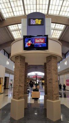 HarMar signs and logo and slogan: "Shopping for Real Life". But why is she on a laptop?